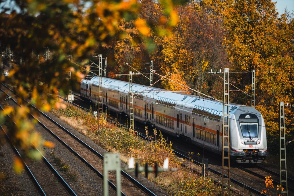 Train traversing colorful autumn scenery in Bielefeld, surrounded by vibrant fall foliage.